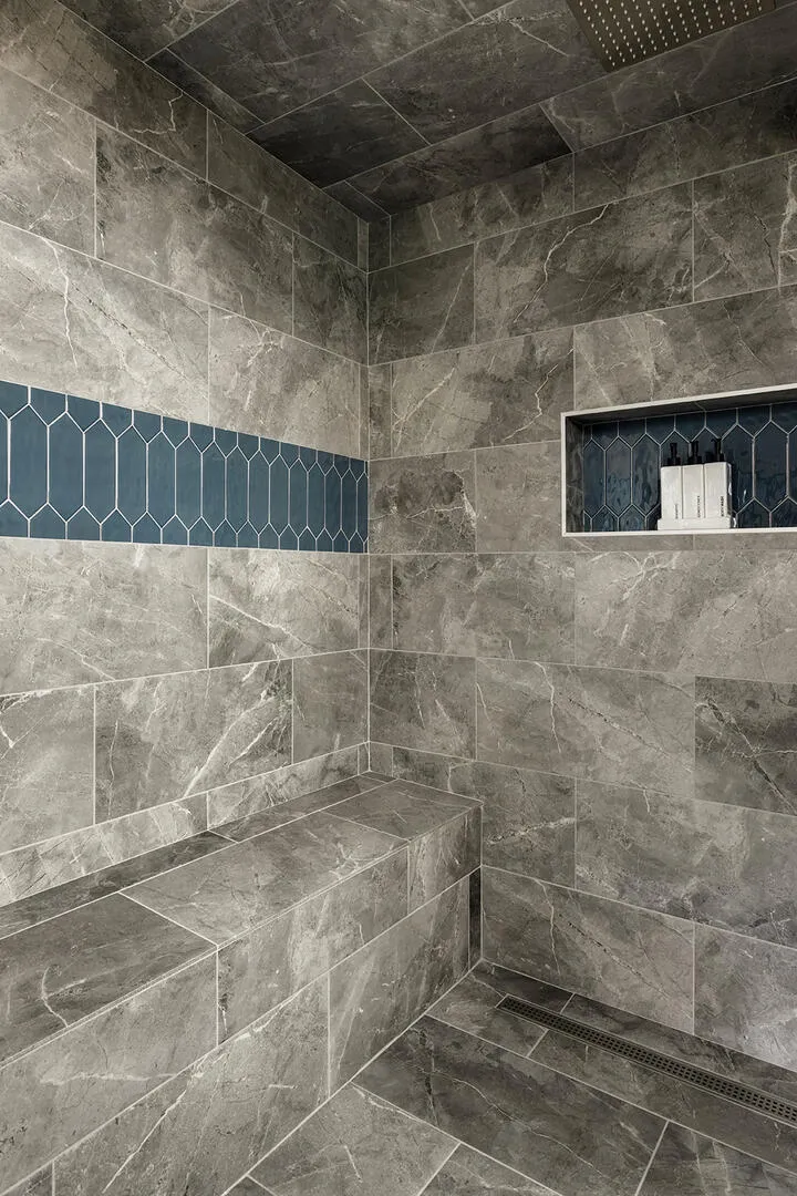 Sleek masculine steam shower design, grey stone look tile with blue accents
