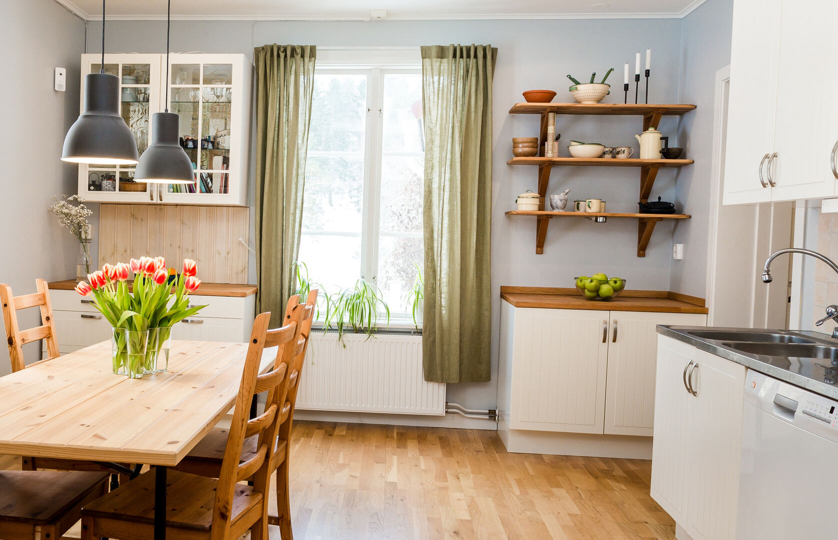 cozy cottage kitchen with white cabinetry, hardwood floors and green accents