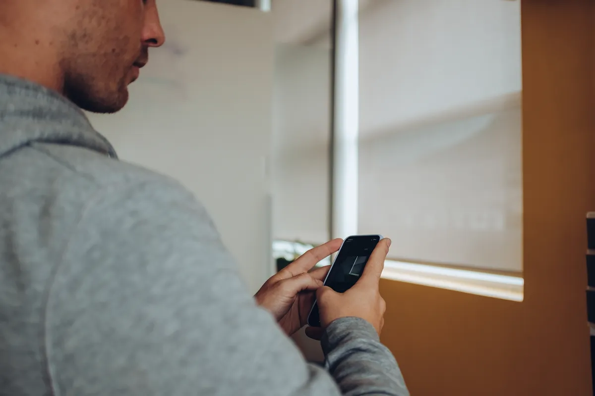 man holding smartphone using app at home