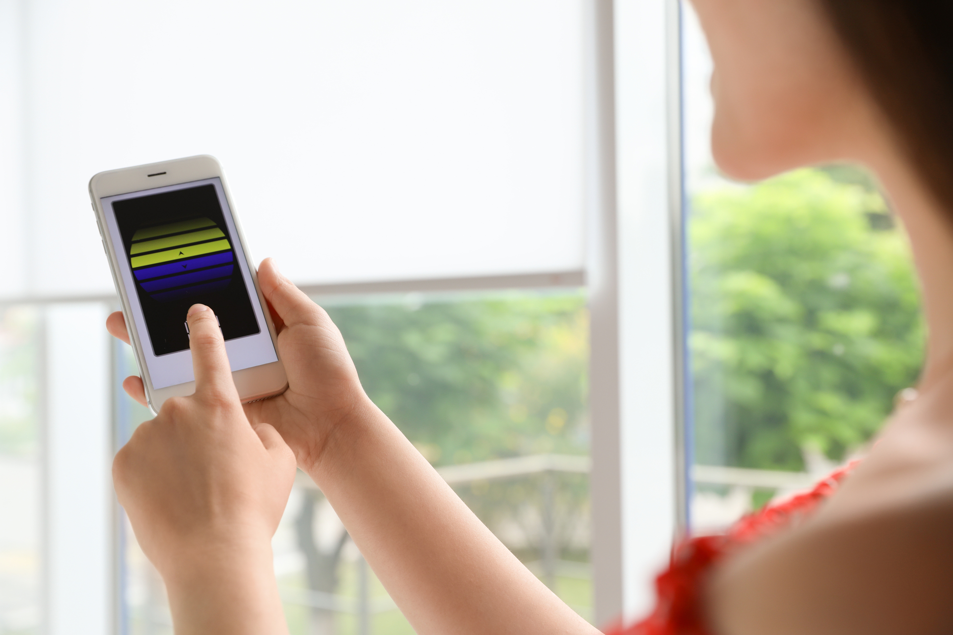 woman taps smartphone near window with green view