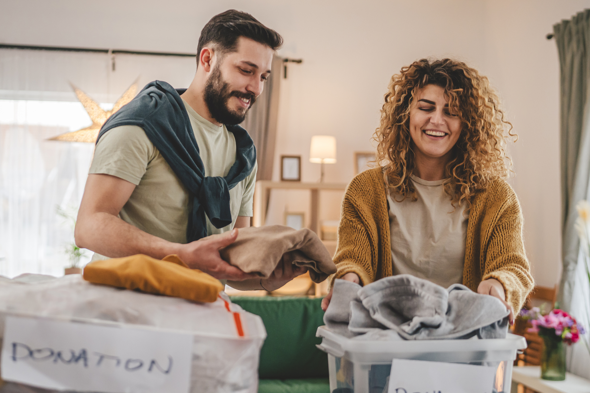 Smiling Couple Sorting Clothes for Donation in Their Living Room