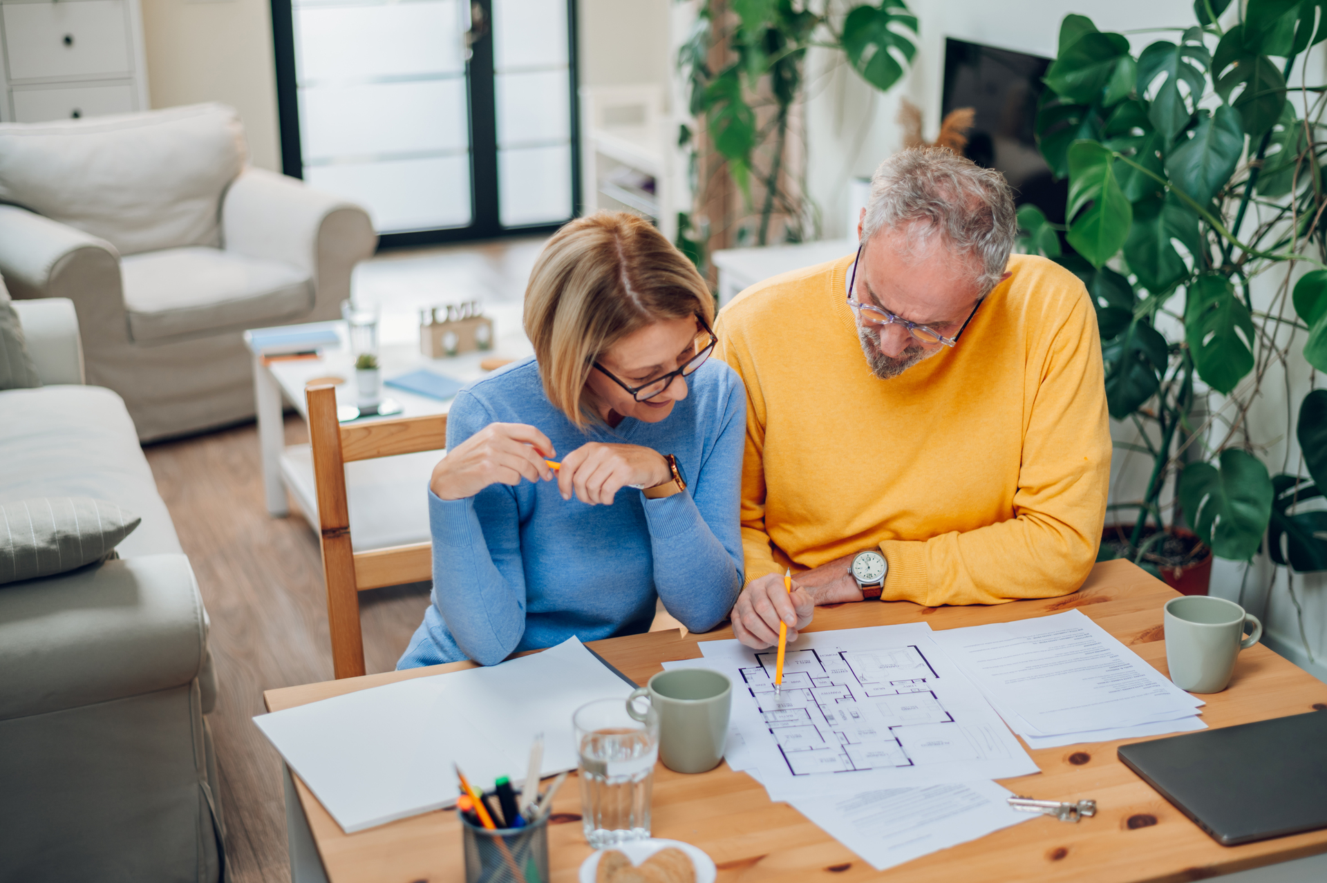 Couple Reviewing Blueprints at Home on Wooden Table