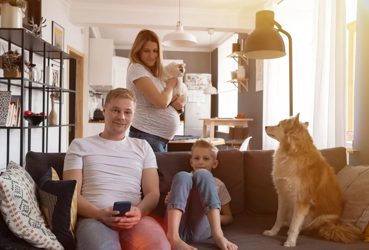 happy family sitting in the living room on the sofa with their son, a dog, and a cat