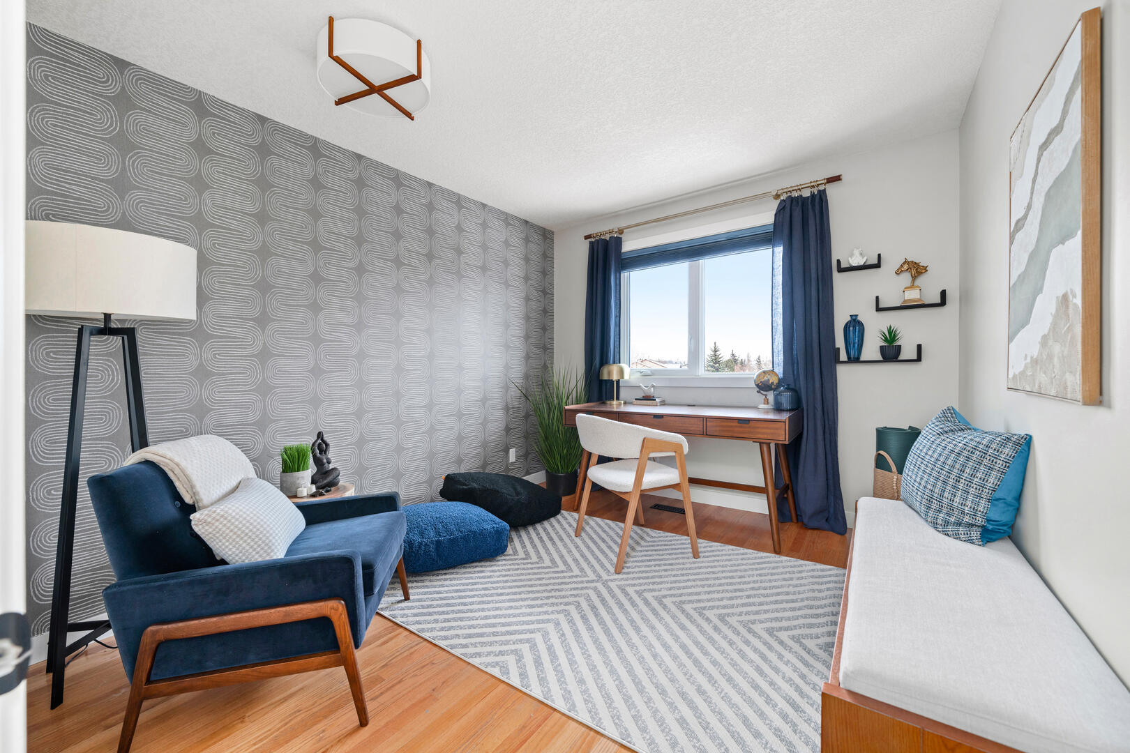 Clean modern home office with wood accents and wallpaper feature with blue chair