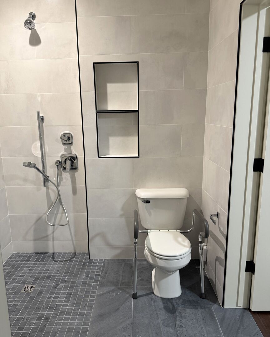 Modern black and white bathroom with chrome fixtures and accessible curbless shower.