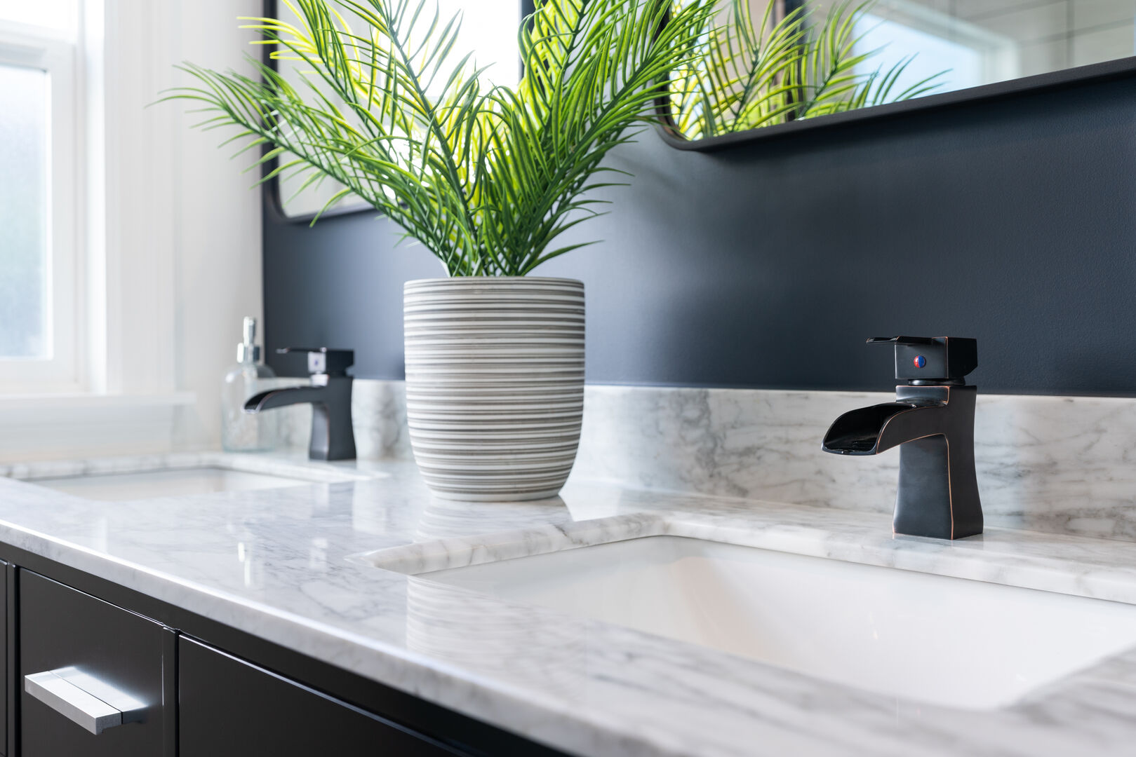 Close up of a black and white bathroom with double vanity sink in white and gray marble and dark grey walls