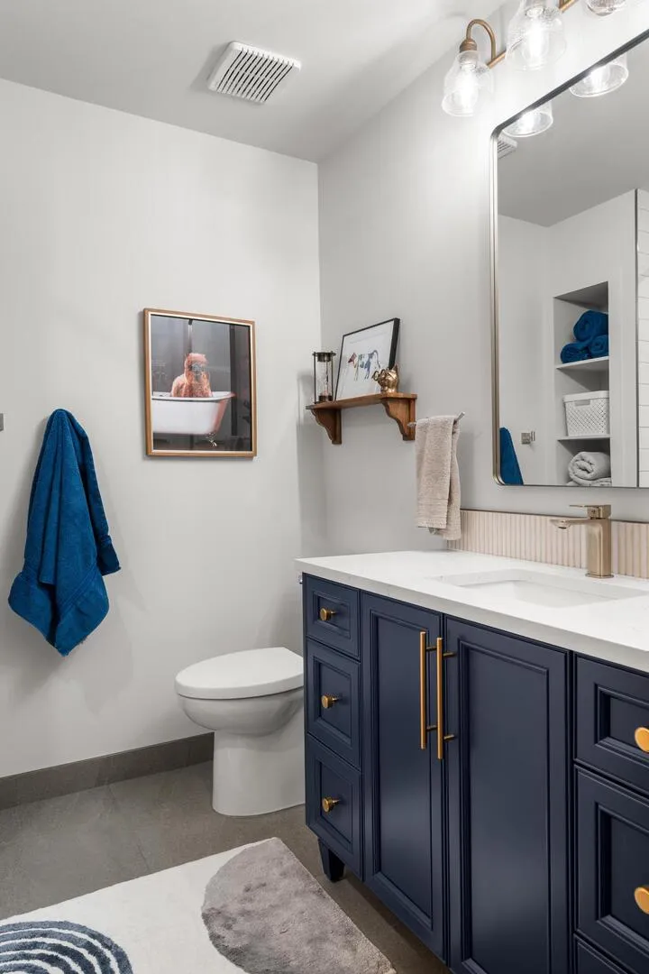 Guest bathroom vanity with dark blue cabinets and brass pull handles