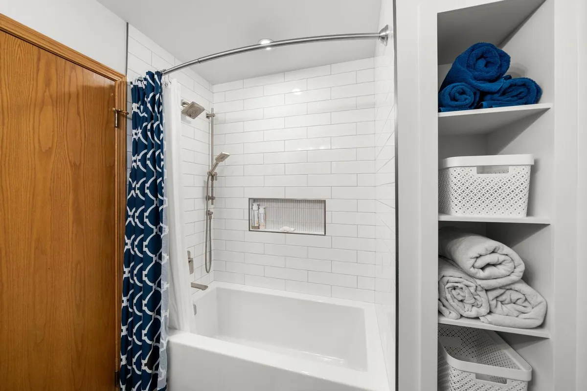 Modern shower with clean large tiles and storage solution for towels