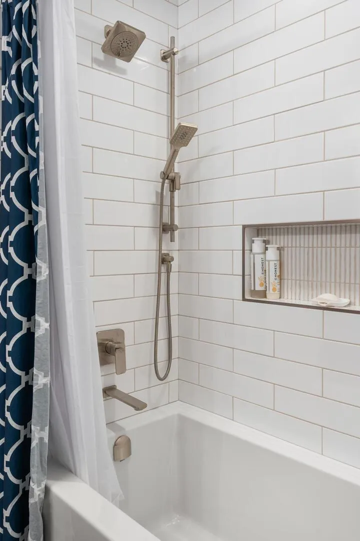 Closeup of modern shower with clean large tiles and inset shelf for shampoo