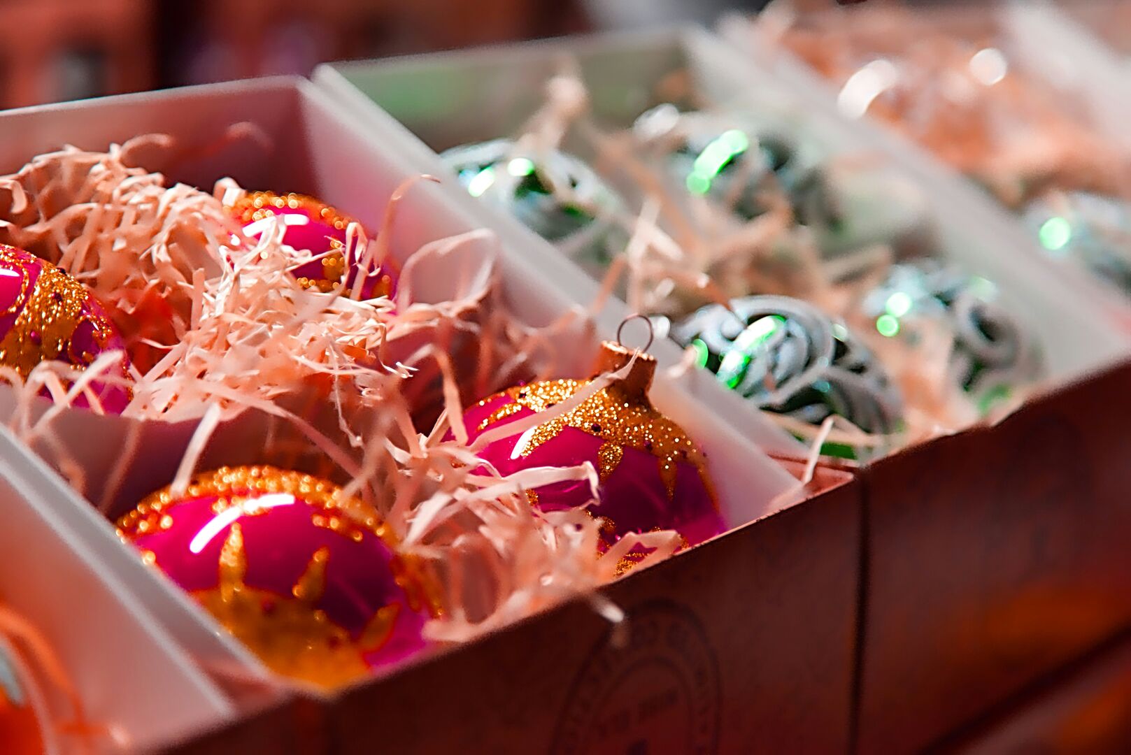 Red and green christmas tree ornaments in a brown box.