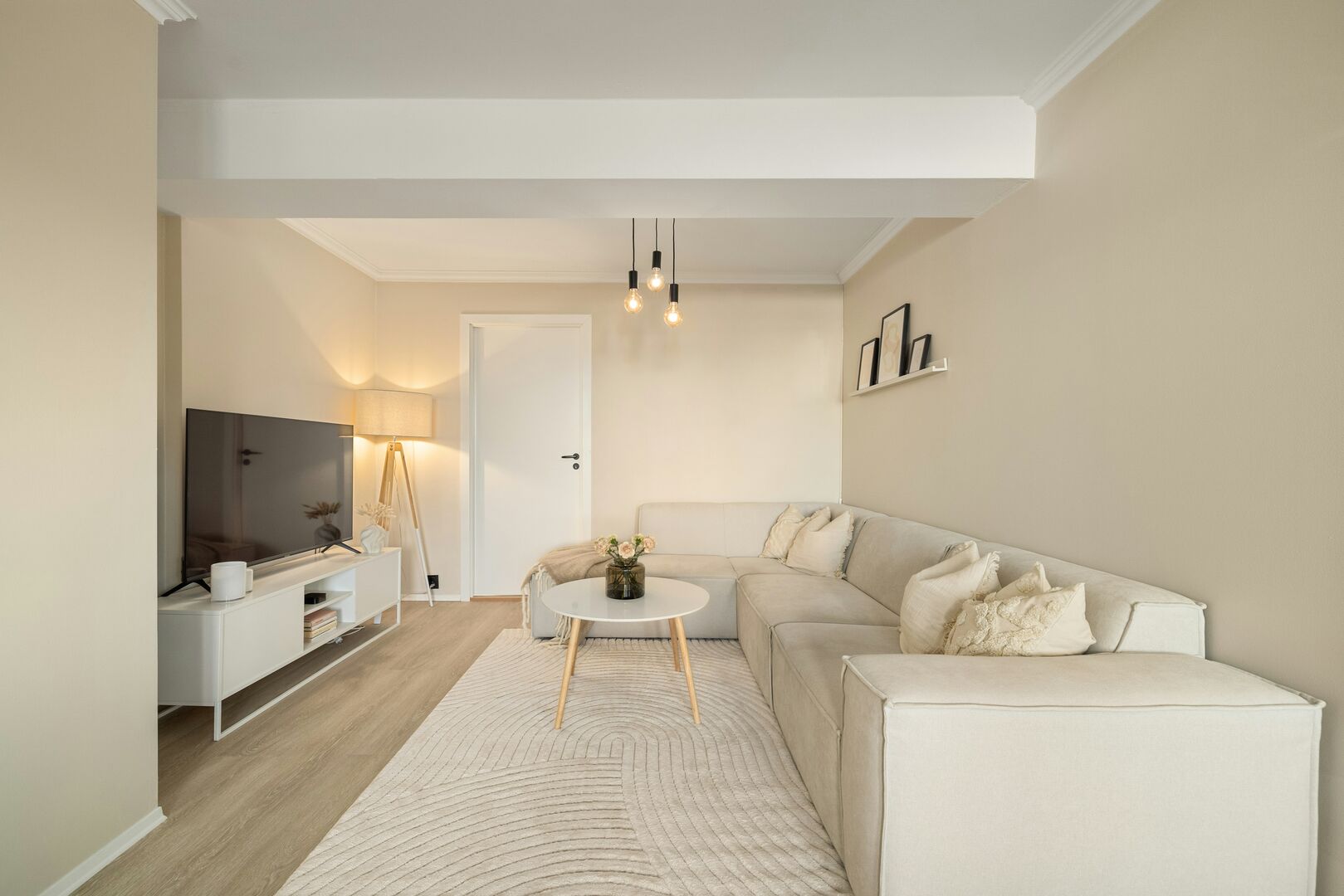 Living room with a large cream coloured sectional sofa, and a cozy boho inspired abstract area rug.