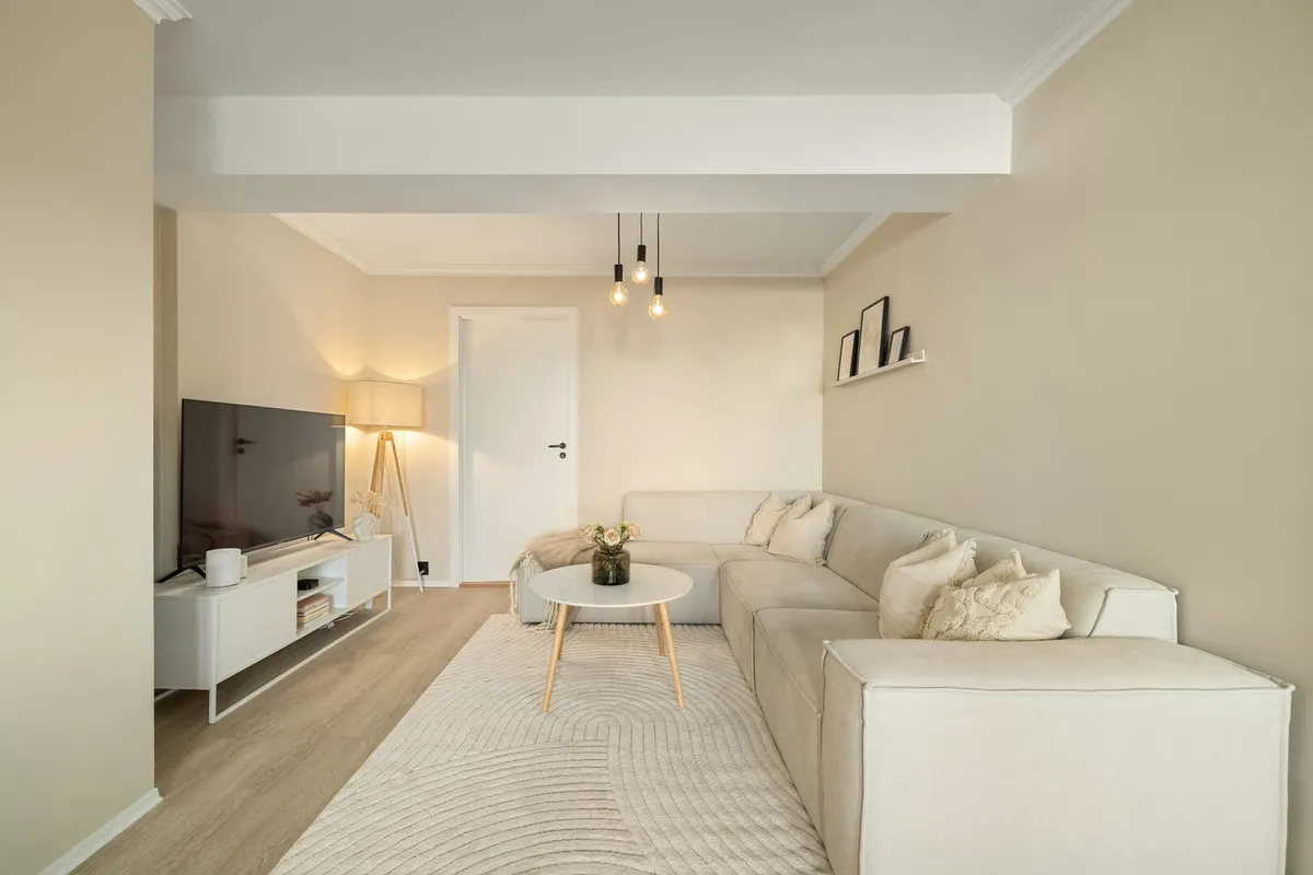 Living room with a large cream coloured sectional sofa, and a cozy boho inspired abstract area rug.