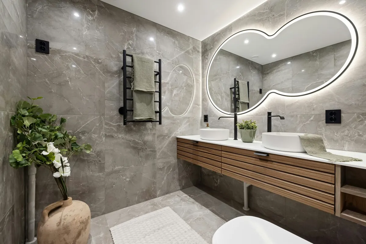Contemporary powder room with wood vanity, grey tile and whimsical LED mirror.