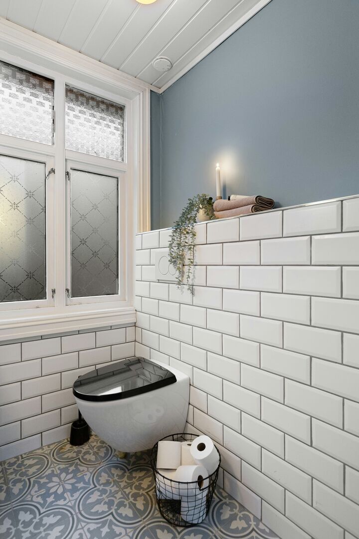 Modern blue and white bathroom with fun patterned floor tile and blue accent wall.