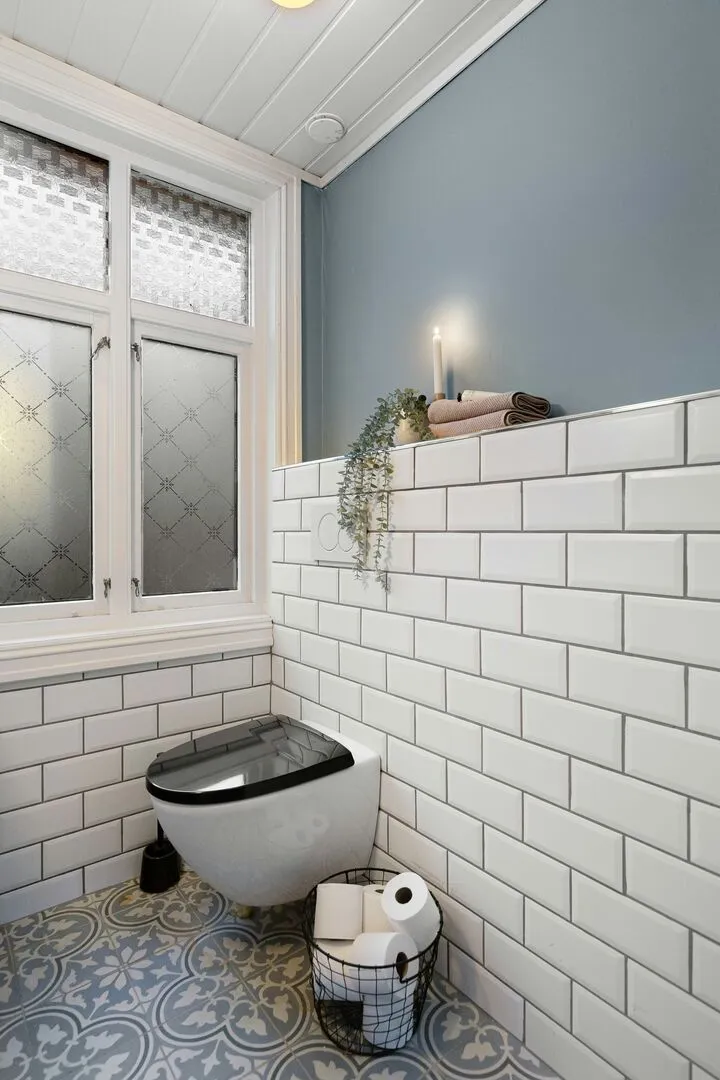 Modern blue and white bathroom with fun patterned floor tile and blue accent wall.