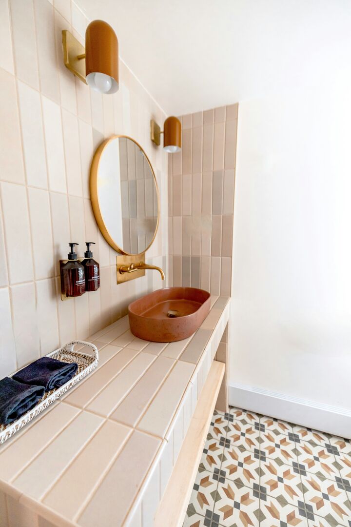 Modern powder room with bold geometric tile, terracotta and gold accents.