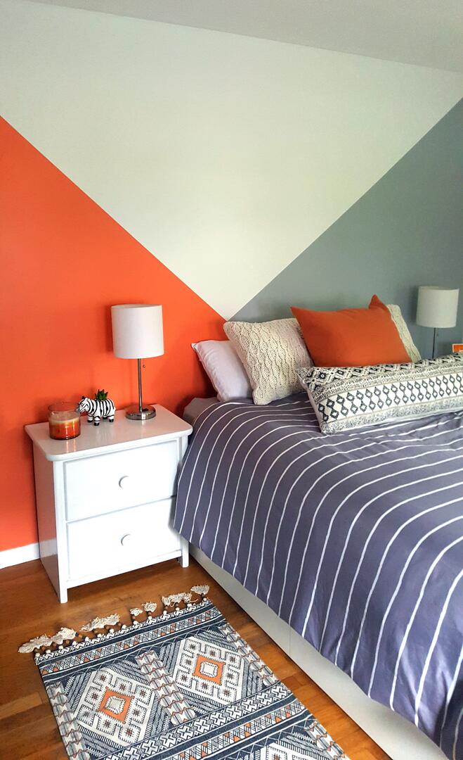 A cozy bedroom with a feature wall with intersecting colour blocks