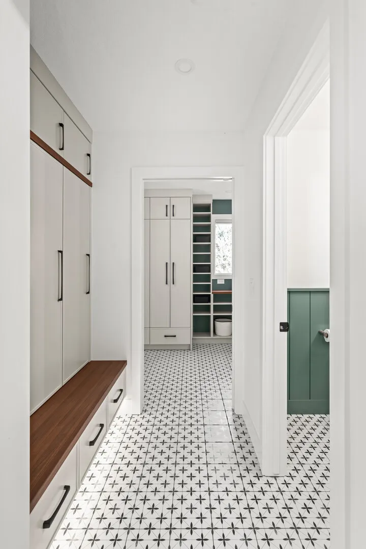 Powder room with green wainscoting, walnut vanity, and patterned floor tile