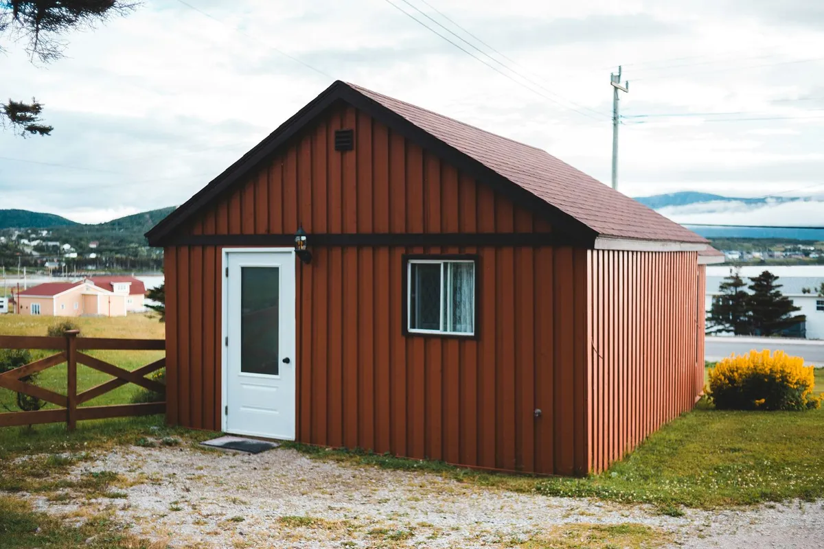 Mahogany stained wood house on a large acreage with black wood trim and a white exterior door