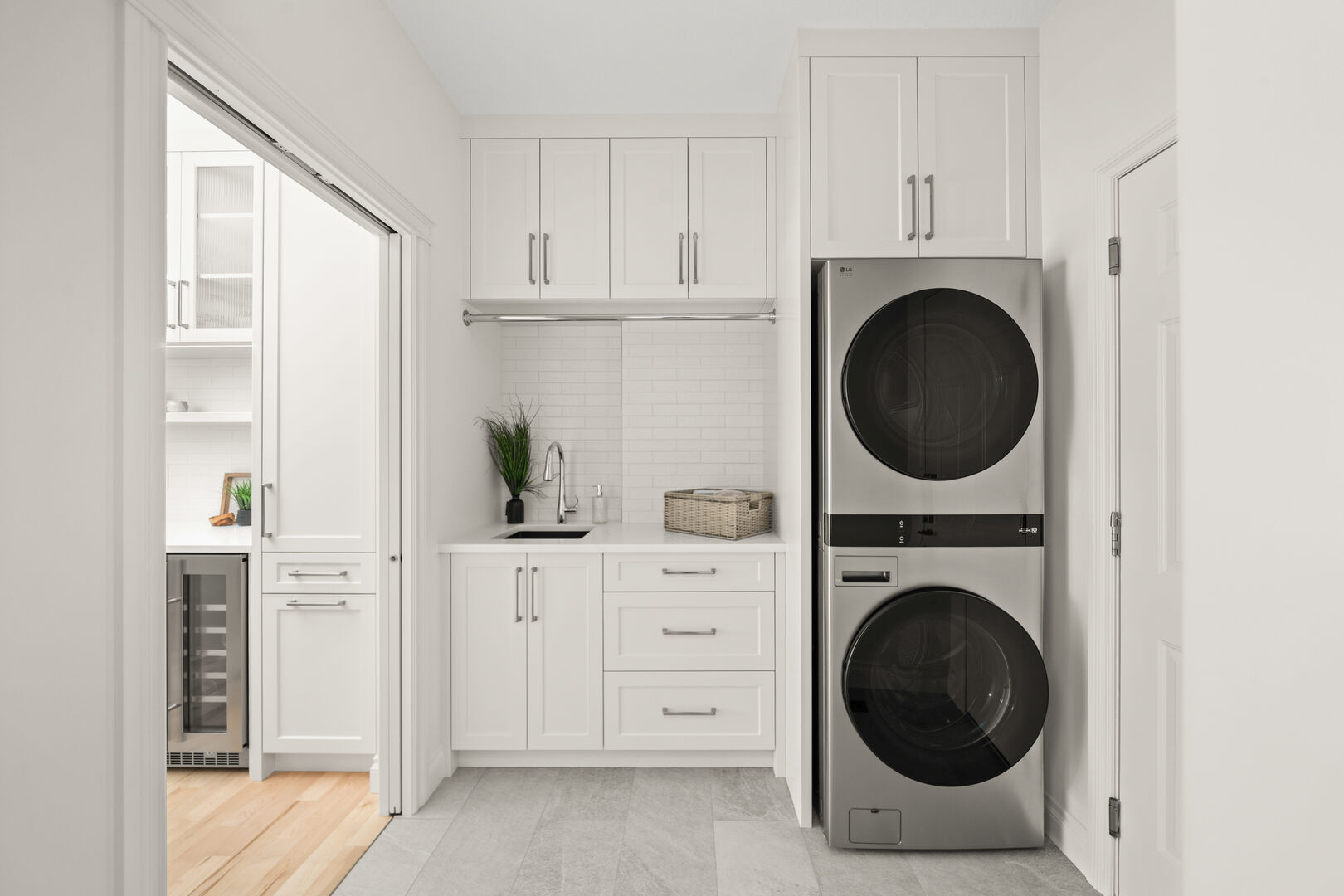Laundry room with stacked washer and dryer, black sink, and white cabinetry