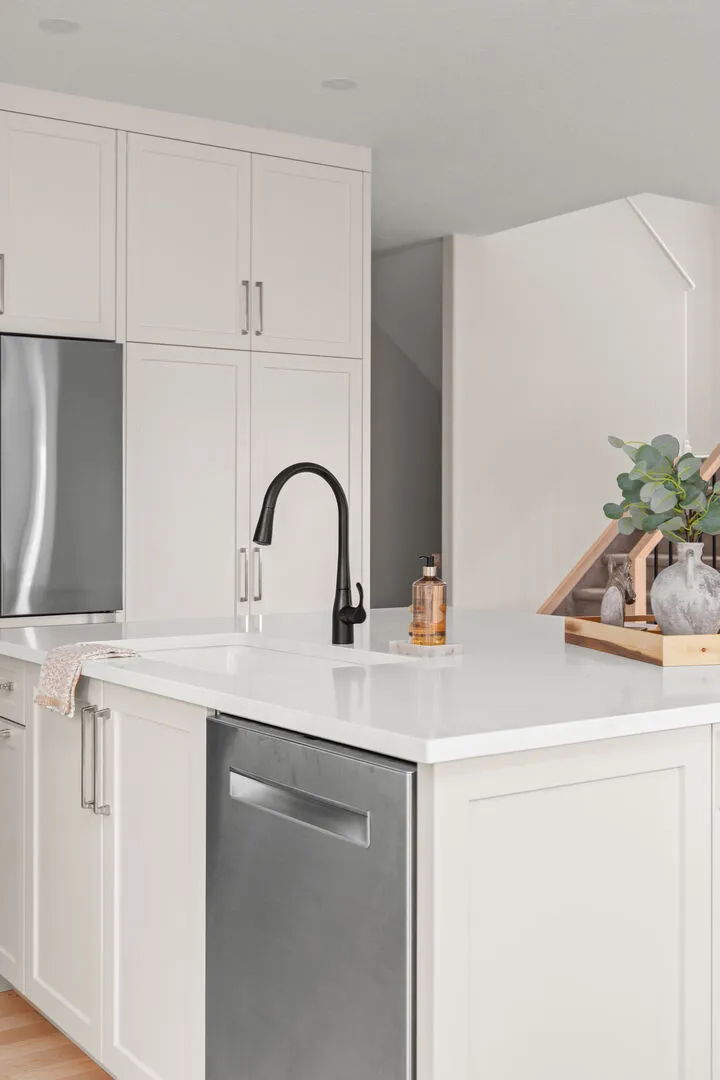 White kitchen with a large island, dining table, and stainless refrigerator