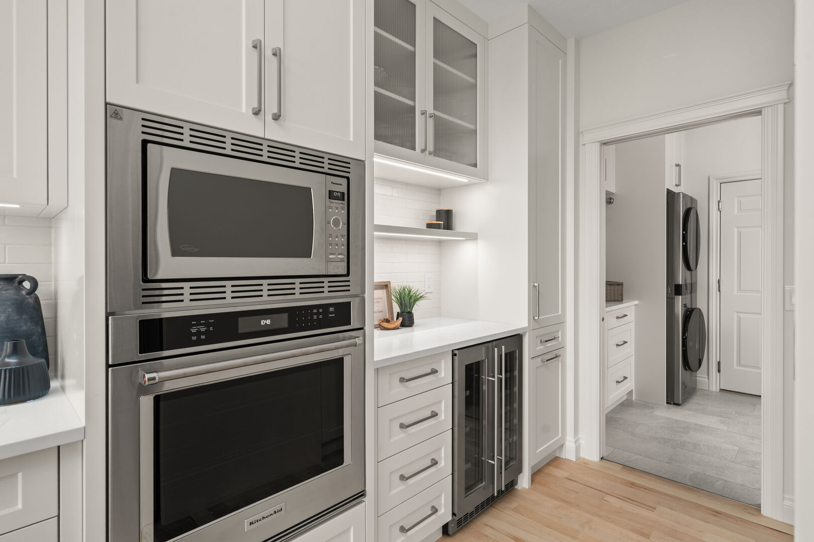 Butler's pantry with built-in ovens, wine fridge, and view into the laundry room