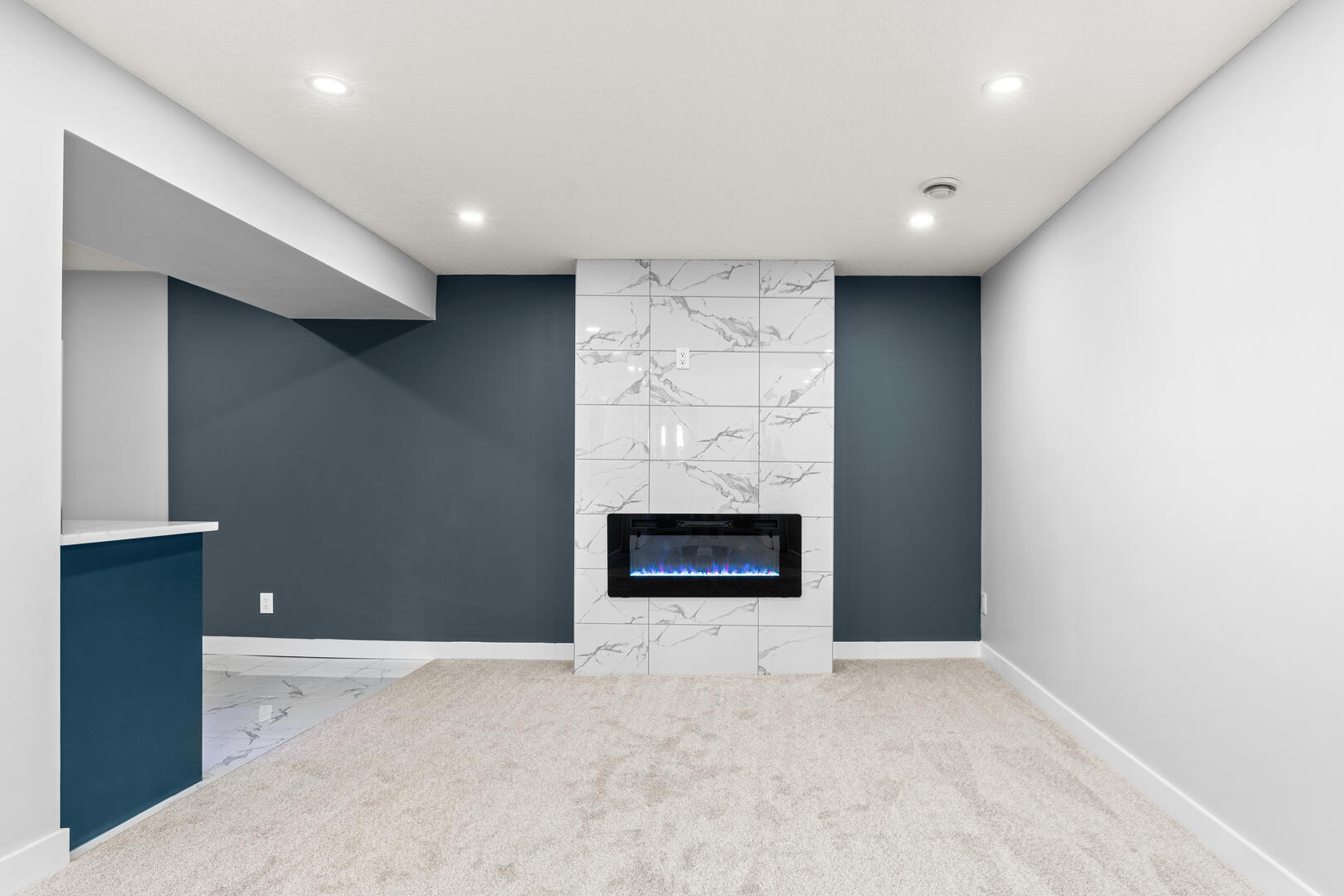 Blue and white basement rec room with marble tiled fireplace