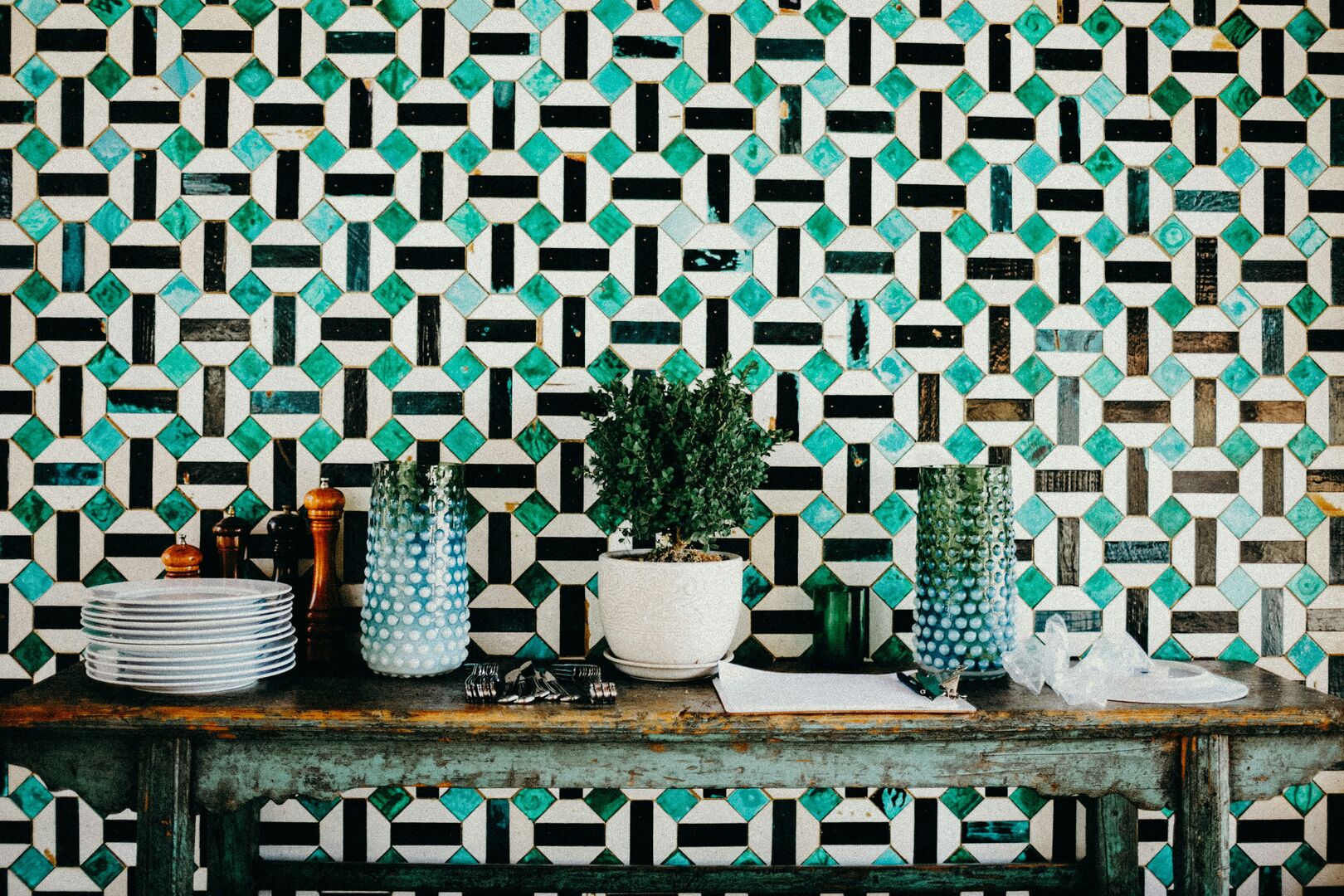 Geometric feature wall with blue and green tones with a rustic wood console table.