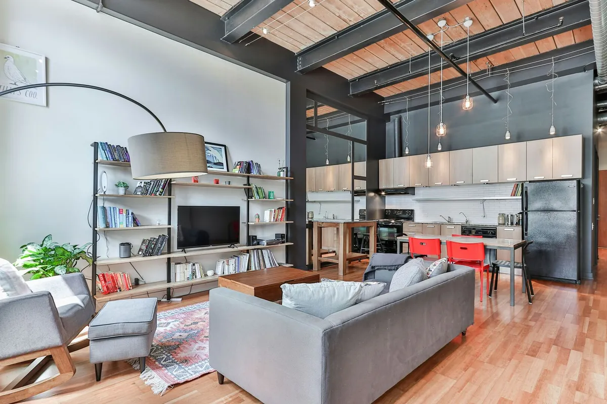 Large grey sofa in an industrial style living room facing a tv unit with a wood and metal bookcase.