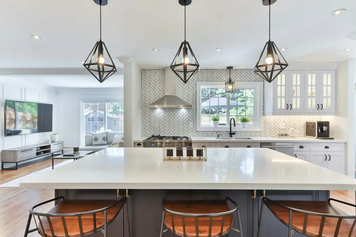 White modern kitchen with chevron tile backsplash and stainless steel appliances