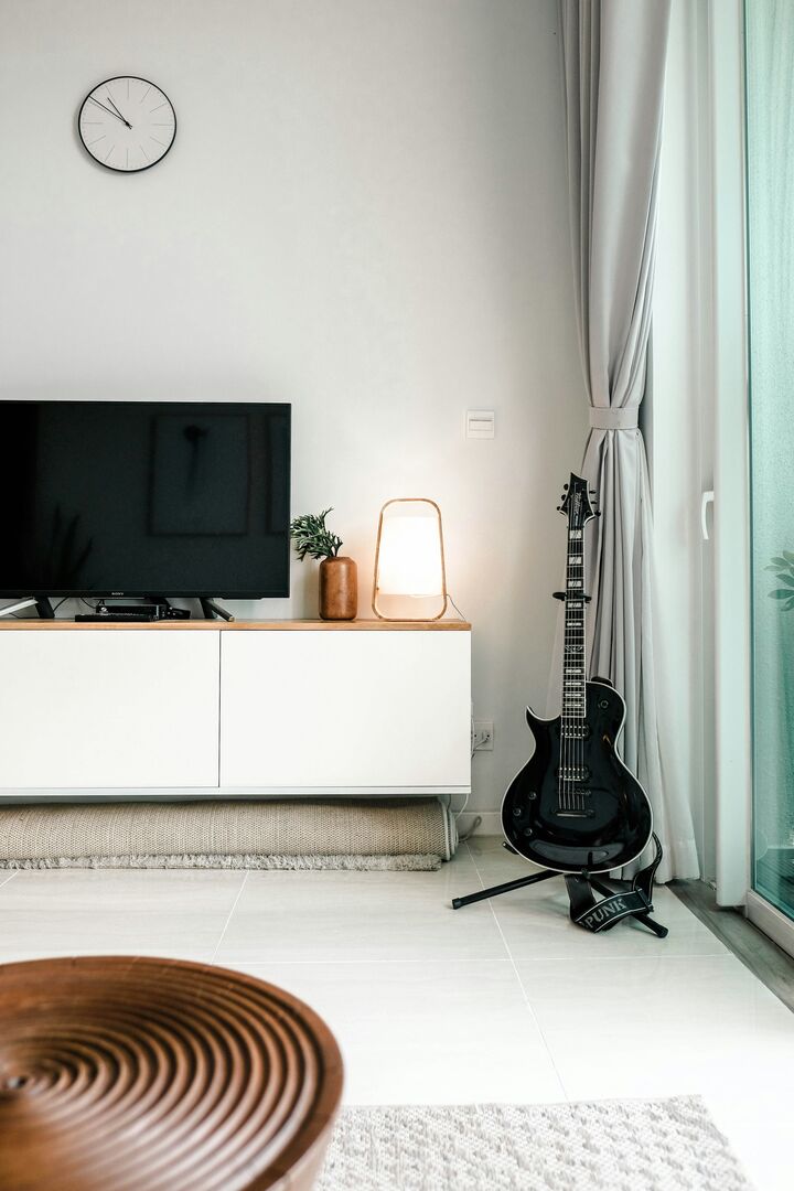 Living room with a white wood tv unit below a large flatscreen tv beside a large patio door window.