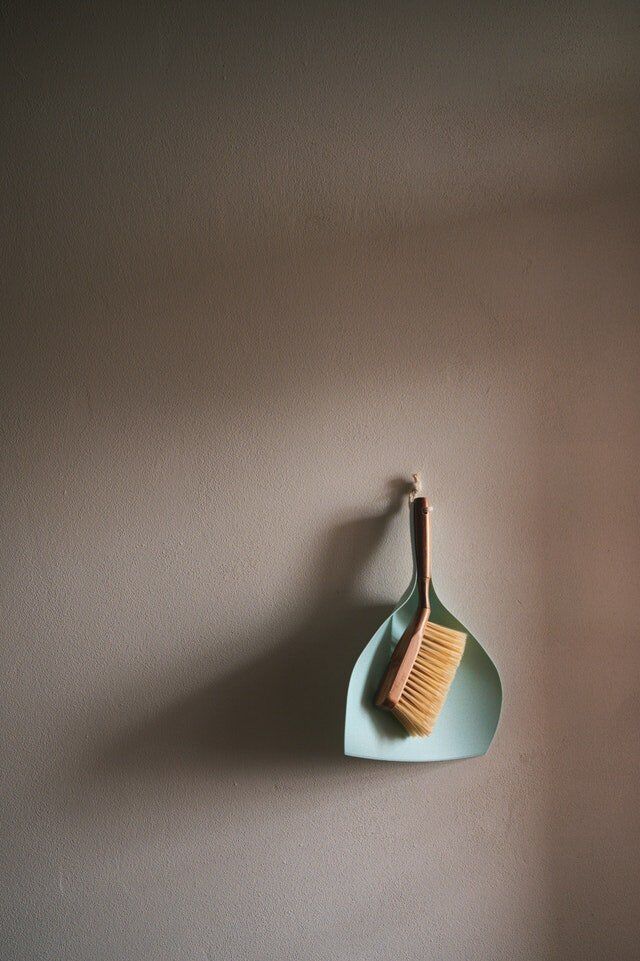 A dustpan and brush hang on a white wall
