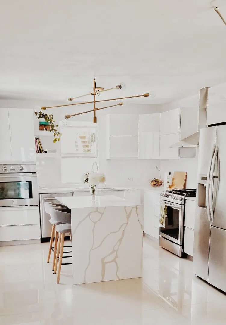 A bright white and gold modern kitchen with many plants