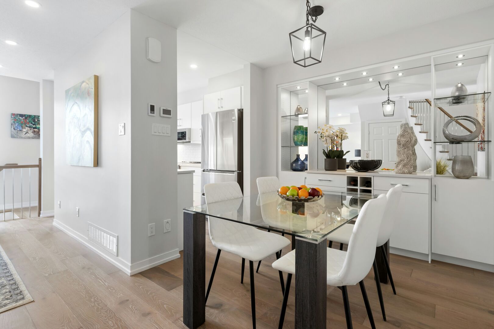 modern dining room that has a wood table with a glass top and a fruit bowl sitting in the center