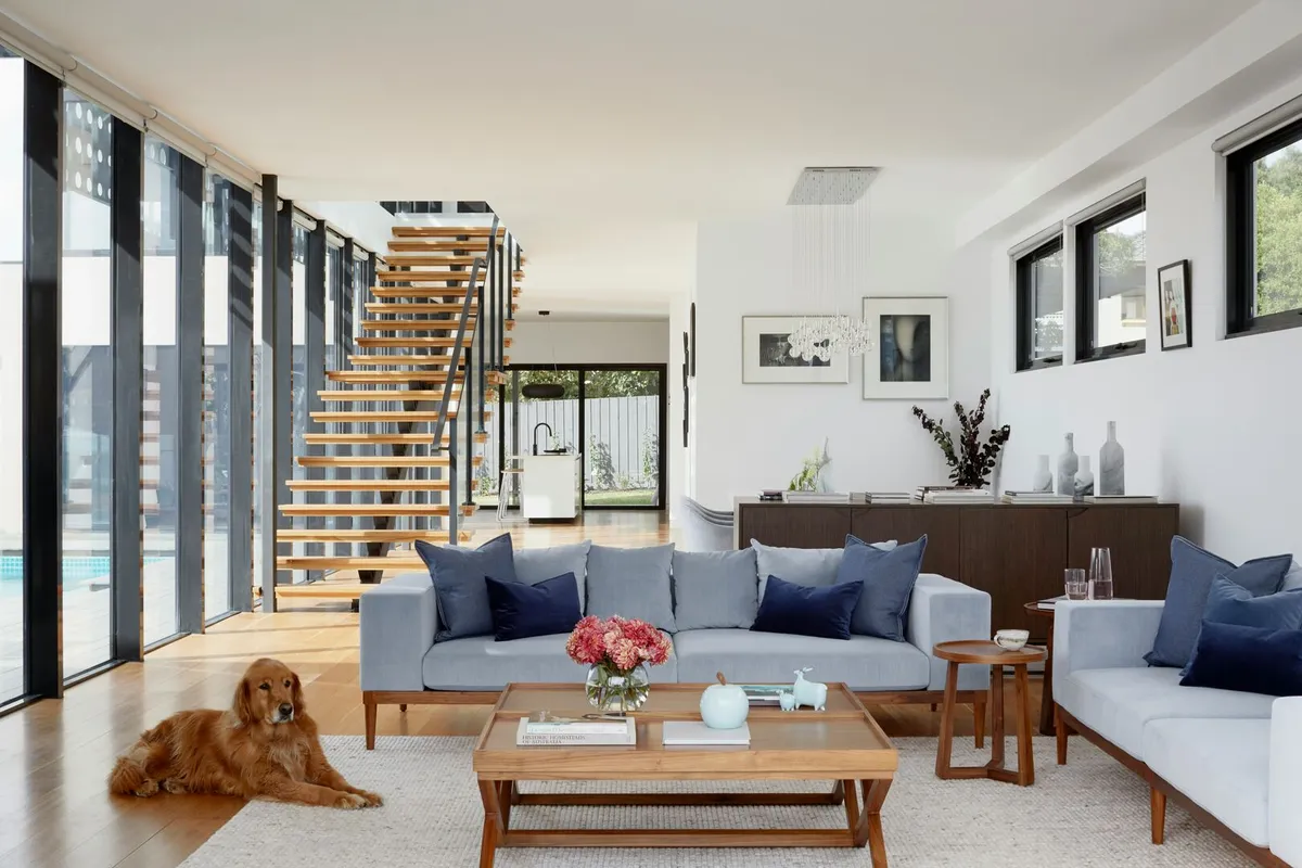 Light and bright living room with a large wood coffee table in front of a grey couch and a golden retriever laying on the floor.