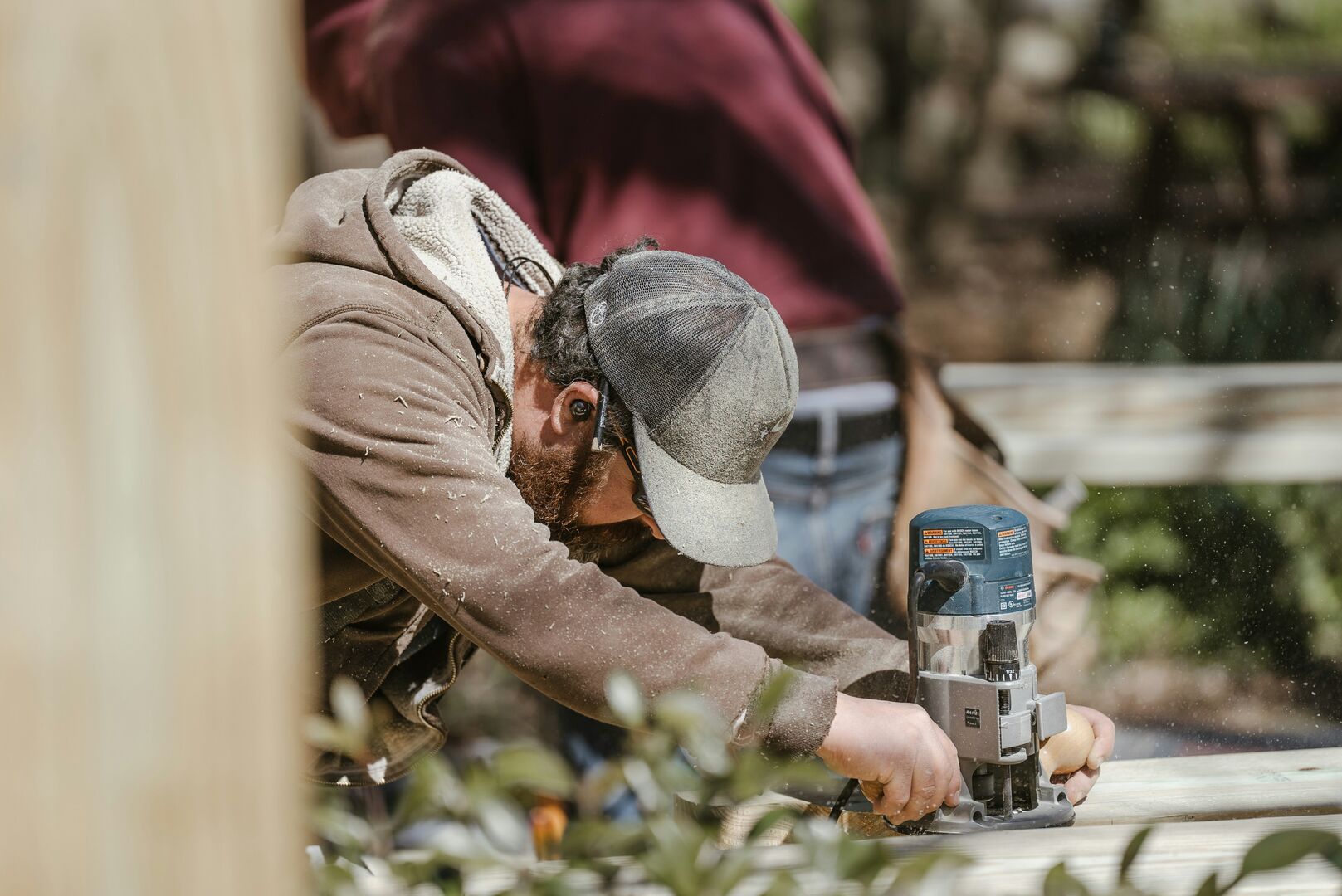 A contractor using a drill on a piece of wood to make a structure.