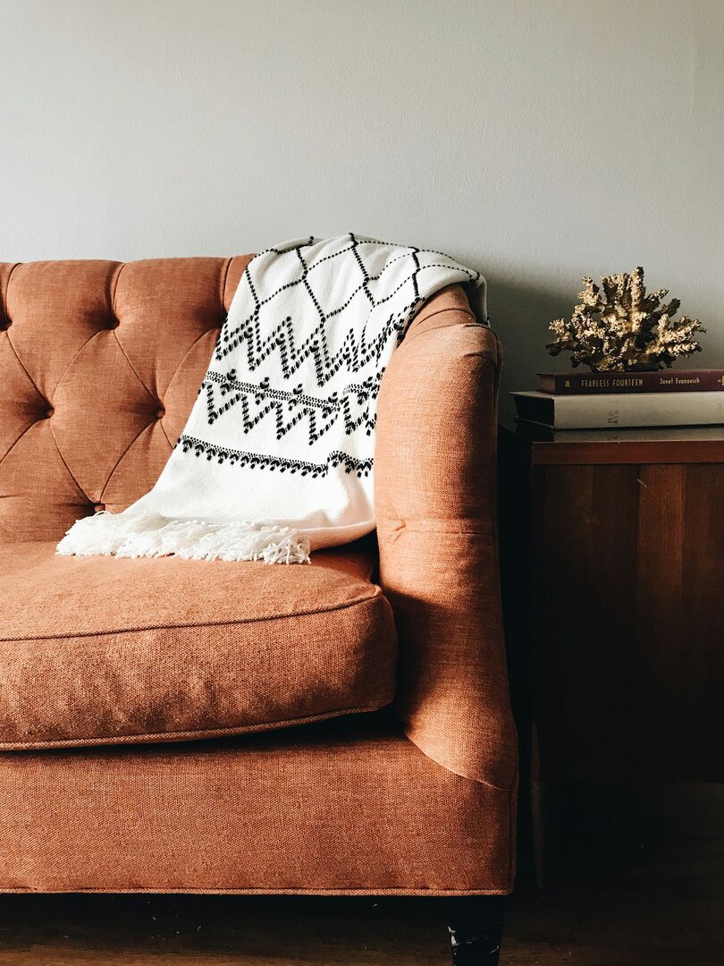 Vintage orange tufted sofa in white room