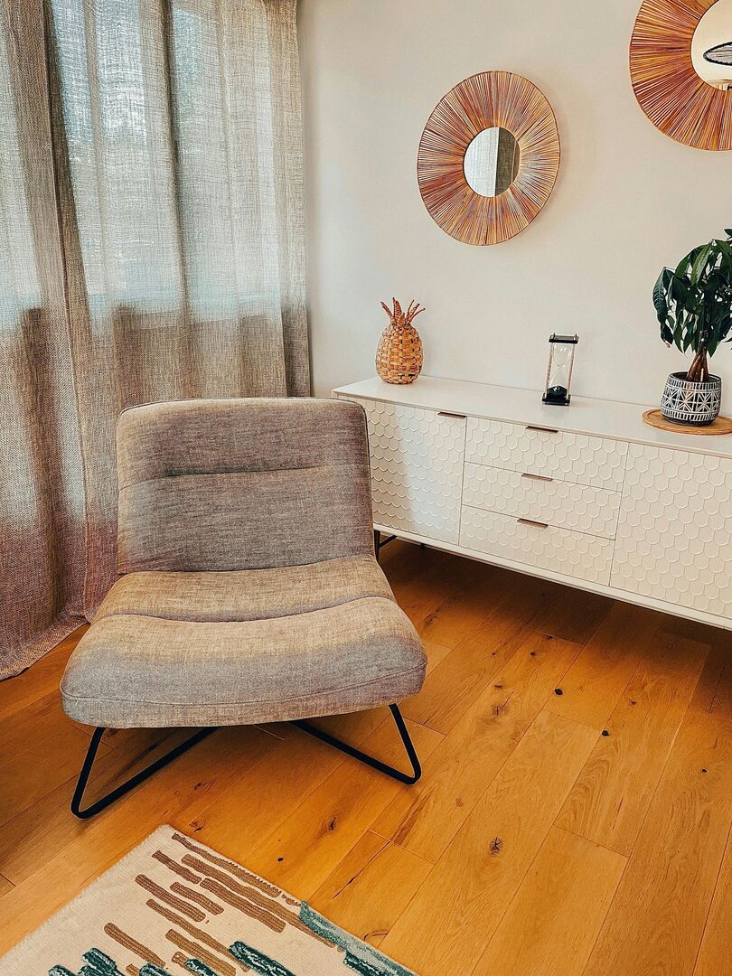 Grey slingback chair in bedroom with hardwood floors